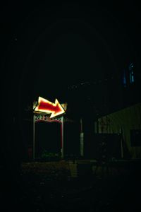red glowing arrow hanging on a hut points in one direction