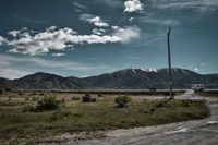 parking lot in the middle of mountains, blue sky, slightly cloudy, power pole, road trip mood, traveling