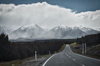 road trip between the mountins, view of a wall of rain passing by the white-covered mountains