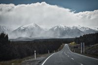 Fotografie, Stra&szlig;enfahrt zwischen den Bergen, Blick auf eine Regenwand, die an den wei&szlig;bedeckten Bergen vorbeizieht, - by Erik Chemnitz