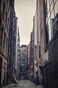 A side street, high house walls and garbage in the corners make the street look rustic.