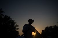 Sunrise, a man paddles his boat. The shades make it look mystical