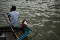 a man waits on his boat with his head hanging down, looking at the water