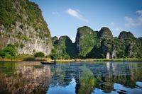 Traders sailing their boat through a bay surrounded by huge karst rocks