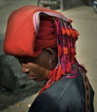 A Red Dao woman stands in the marketplace in a Vietnamese village. She is wearing a traditional dress and a red headdress